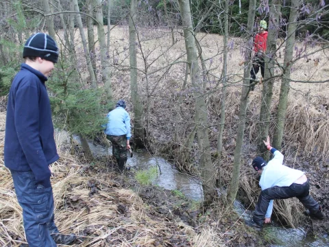 Kluci pouští víčka od ešusu na potoce